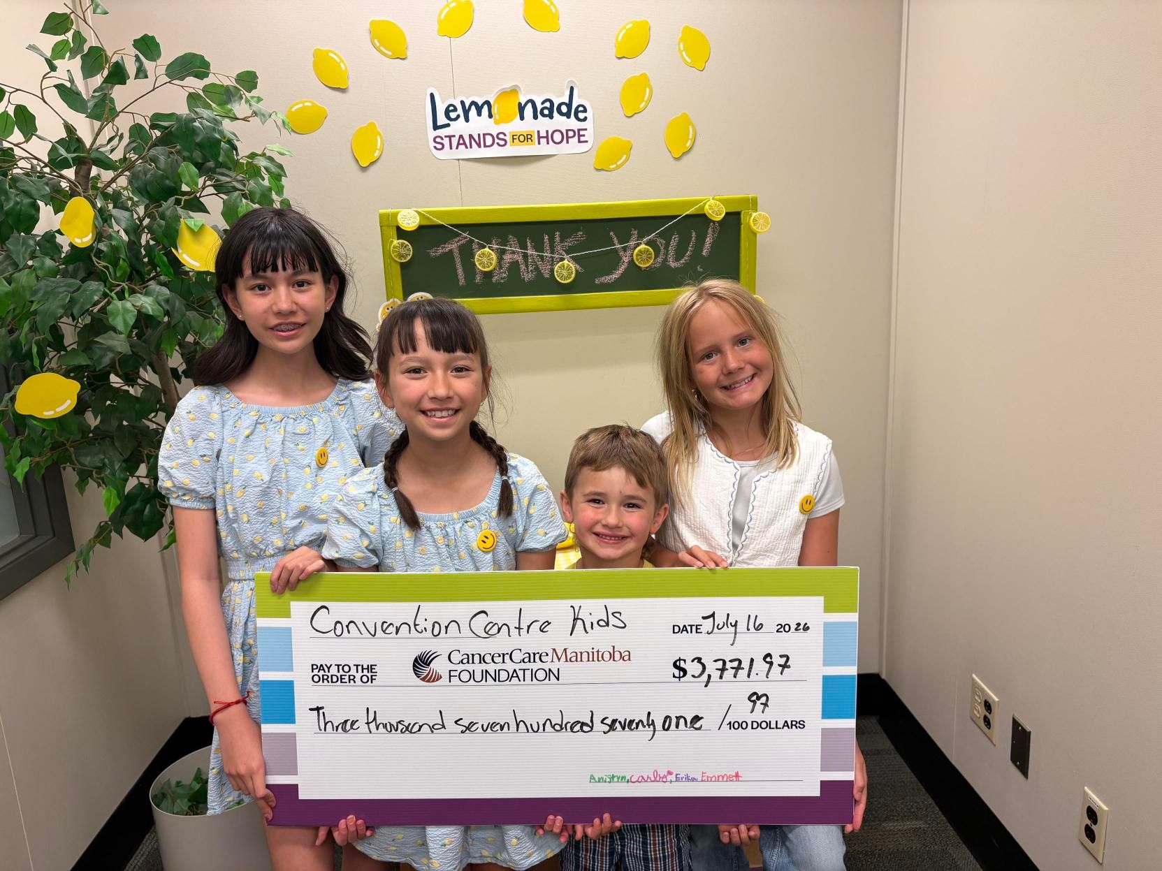 Erika and Carly hold up their cheque at CancerCare Manitoba